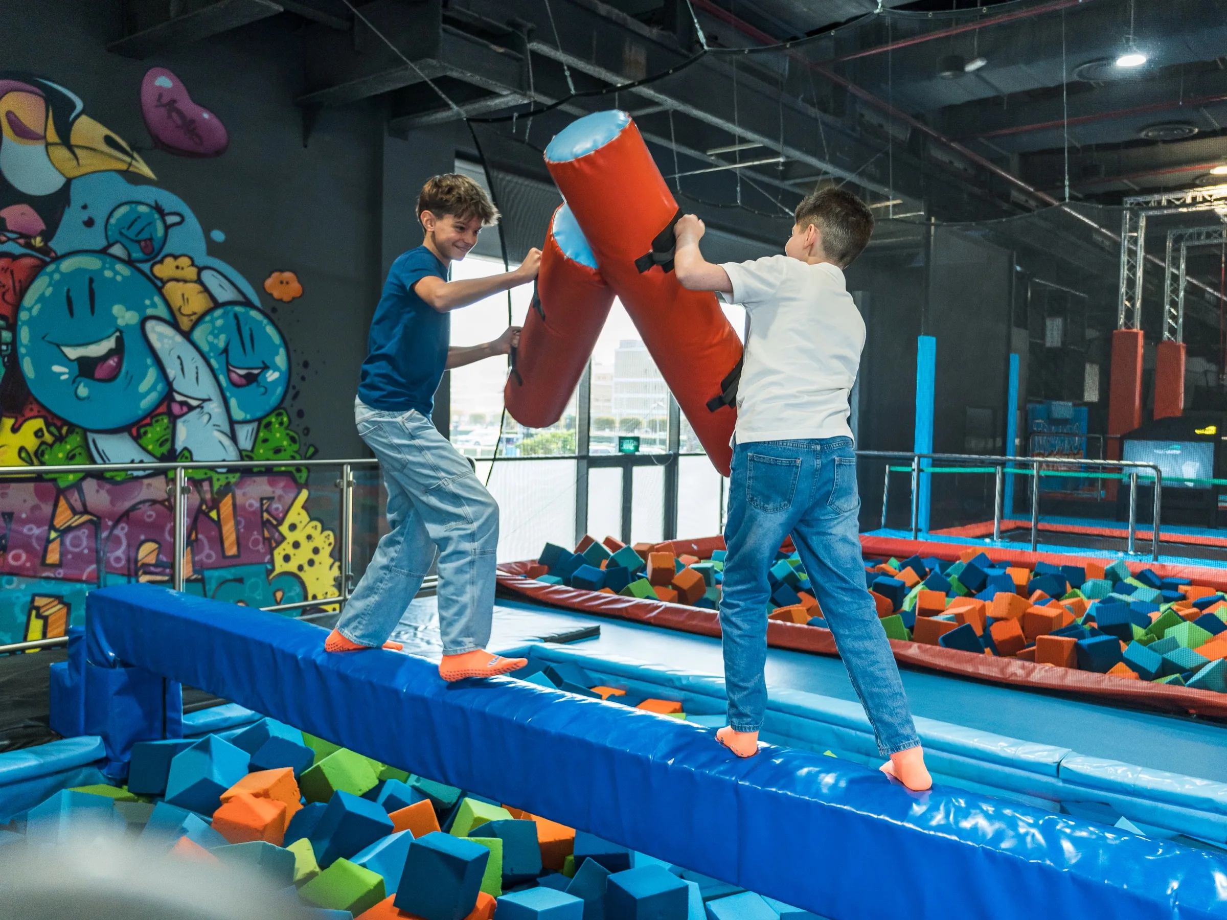Two kids jousting with foam batons at Trampo Kuwait